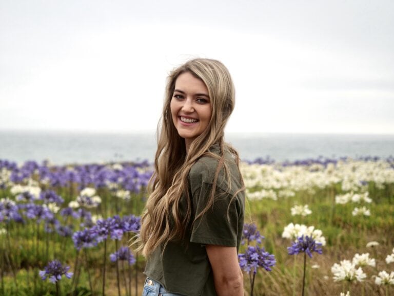 Woman with long hair surrounded by white and purple flowers