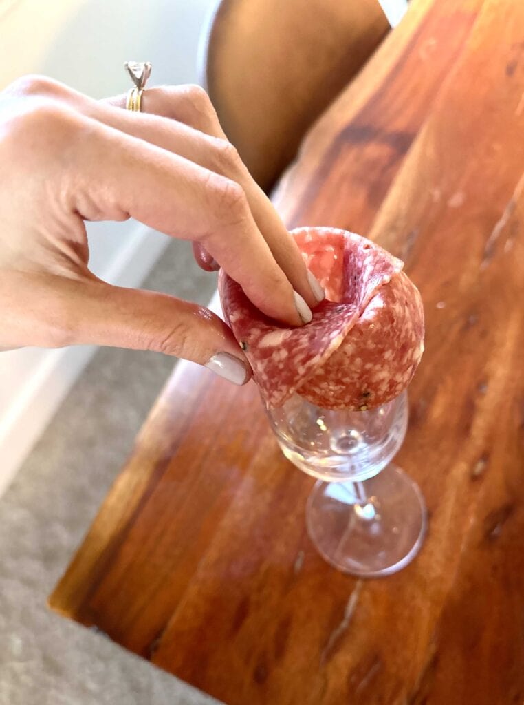 Charcuterie salami rose being created with champagne flute