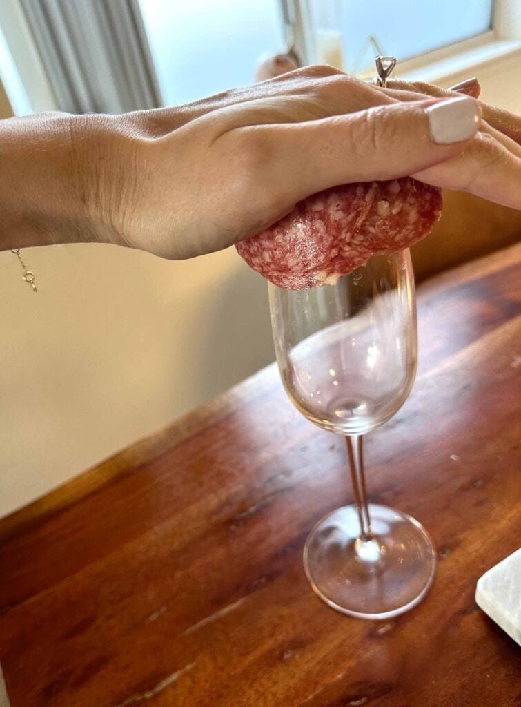 Charcuterie salami rose being created with champagne flute