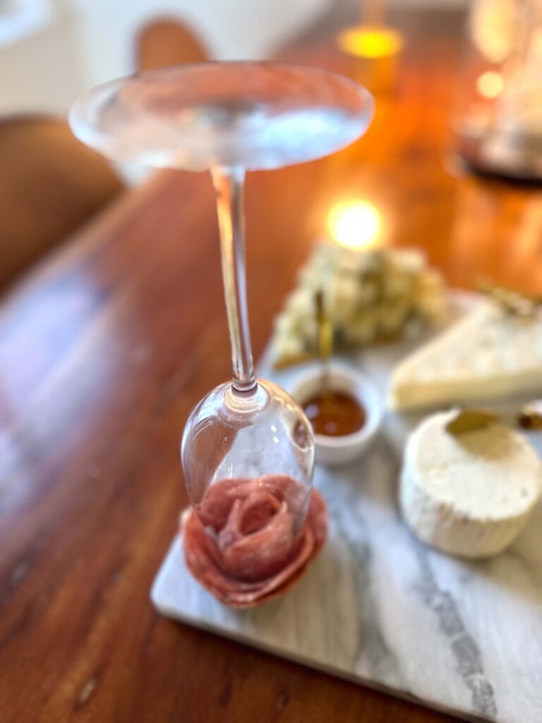 Charcuterie salami rose being created with champagne flute