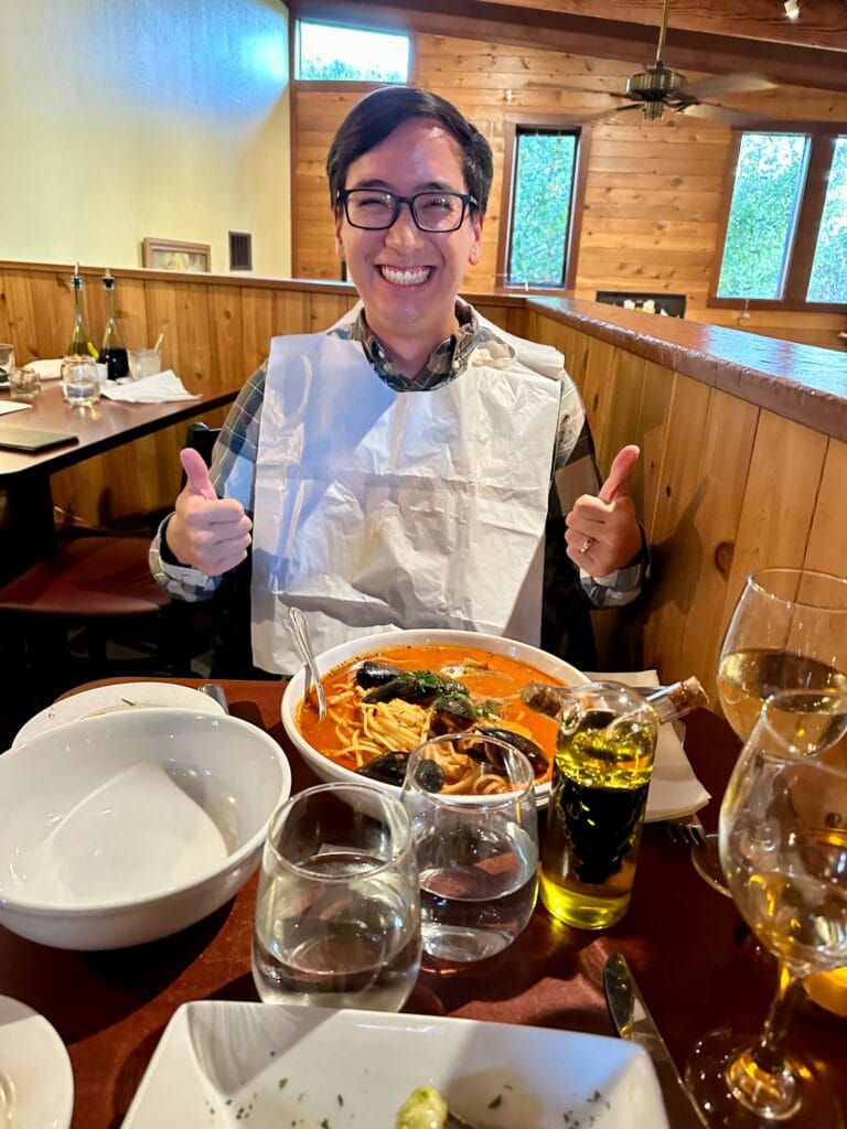 Man smiling in a bib with a seafood dinner at Luna Trattoria