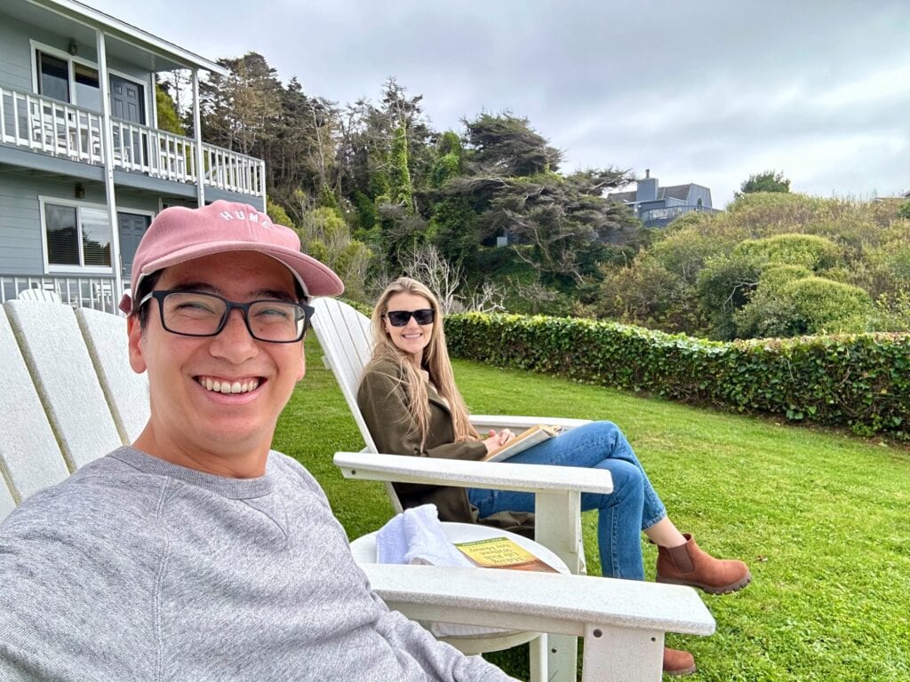 Couple relaxing in white chairs with books and ocean views at Sea Rock Inn