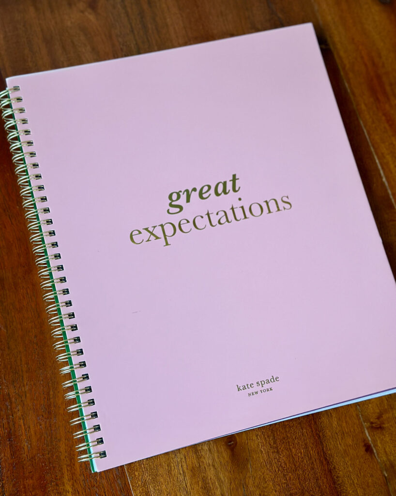 Pink spiral-bound Kate Spade planner with “Great Expectations” on the cover, ideal for organized Enneagram 1s.