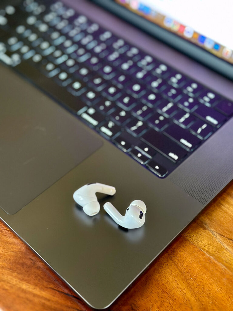 AirPods Pro resting on a MacBook keyboard — sleek tech gift for productivity-loving Enneagram 8s.
