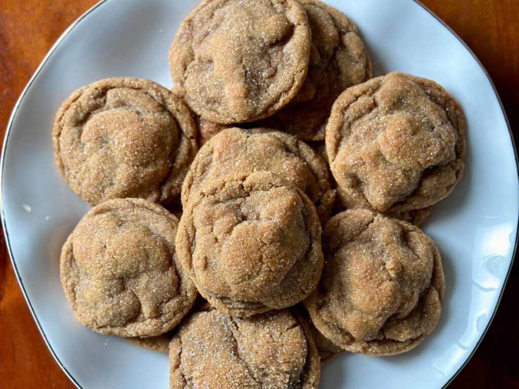 Soft molasses cookies rolled in sugar and baked until crackled, served on a white plate.