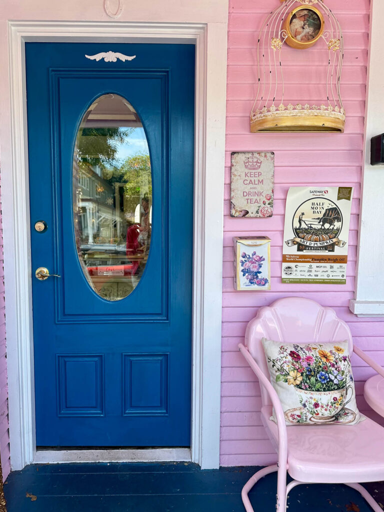 Pink exterior entry door with deep teal trim, accented by whimsical decor and signage.