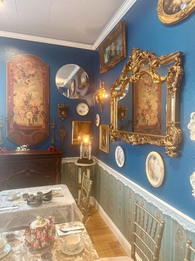 Close-up of ornate gold-framed mirrors and vintage wall art inside the tea room.