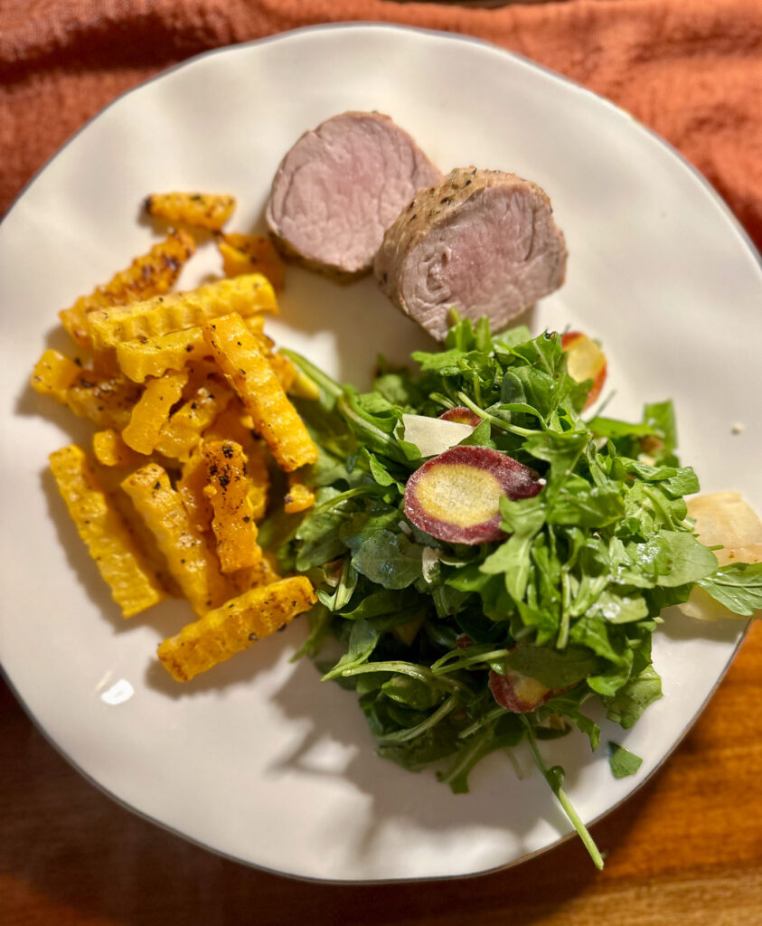 Plate of seared pork tenderloin with roasted butternut squash and salad.
