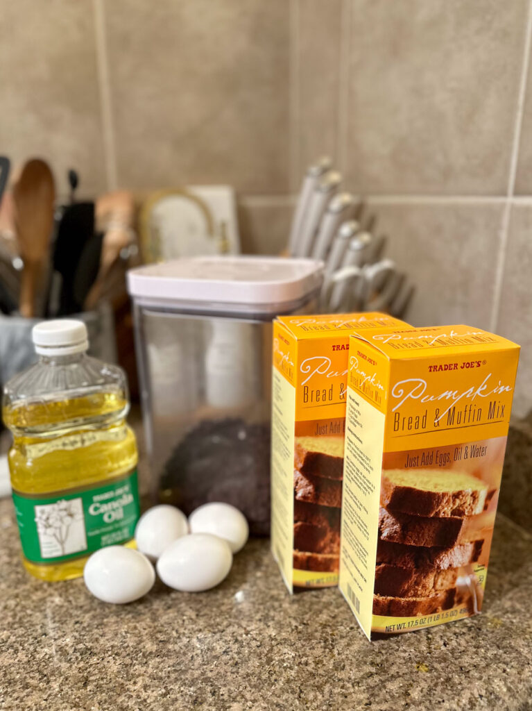 Trader Joe’s pumpkin bread & muffin mix boxes, eggs, oil, sugar, and chocolate chips on a counter.