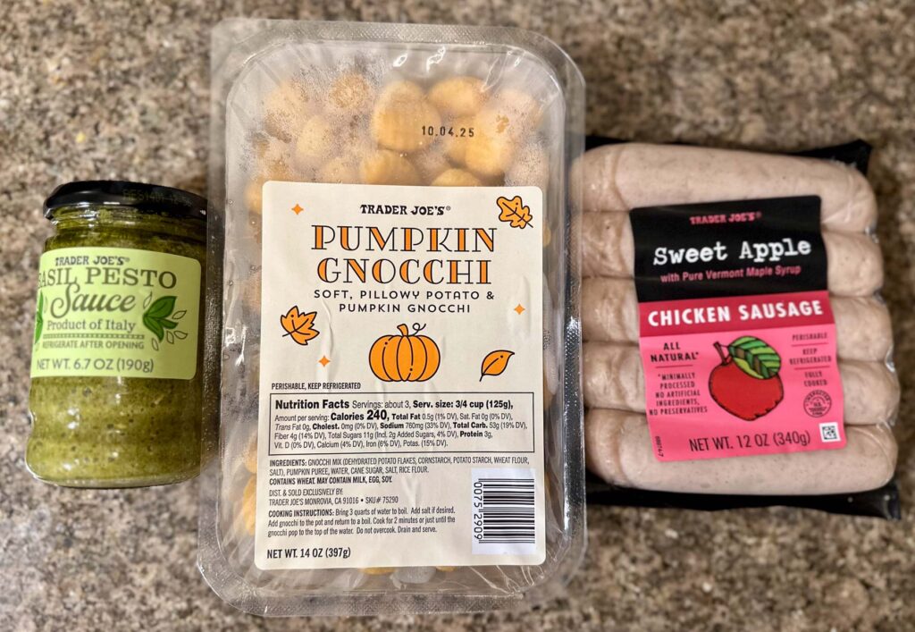 Trader Joe’s pumpkin gnocchi, sweet apple chicken sausage, and basil pesto jar displayed on a counter.