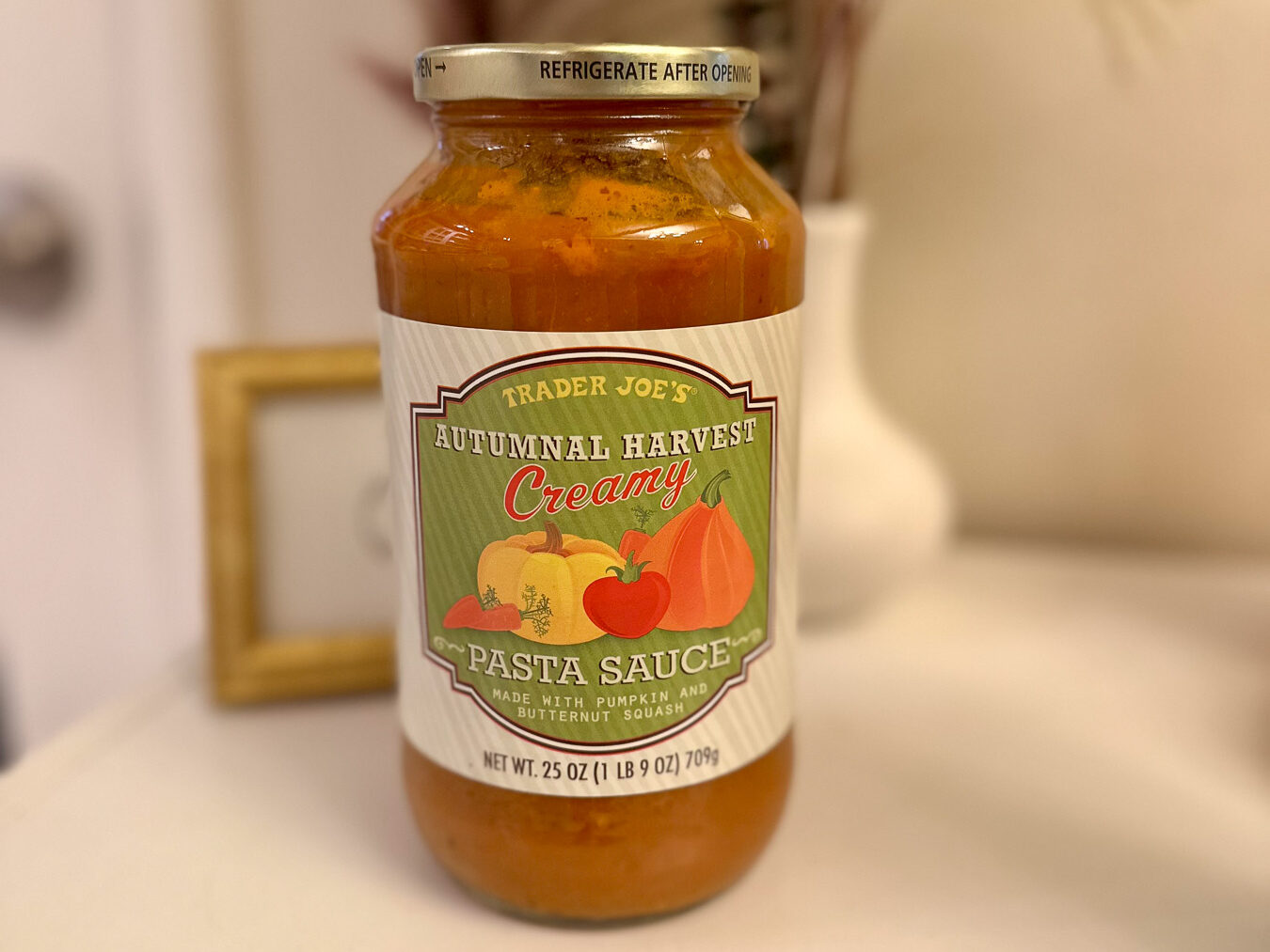 Close-up of Trader Joe’s Autumnal Harvest Creamy Pasta Sauce in a glass jar on a white surface.