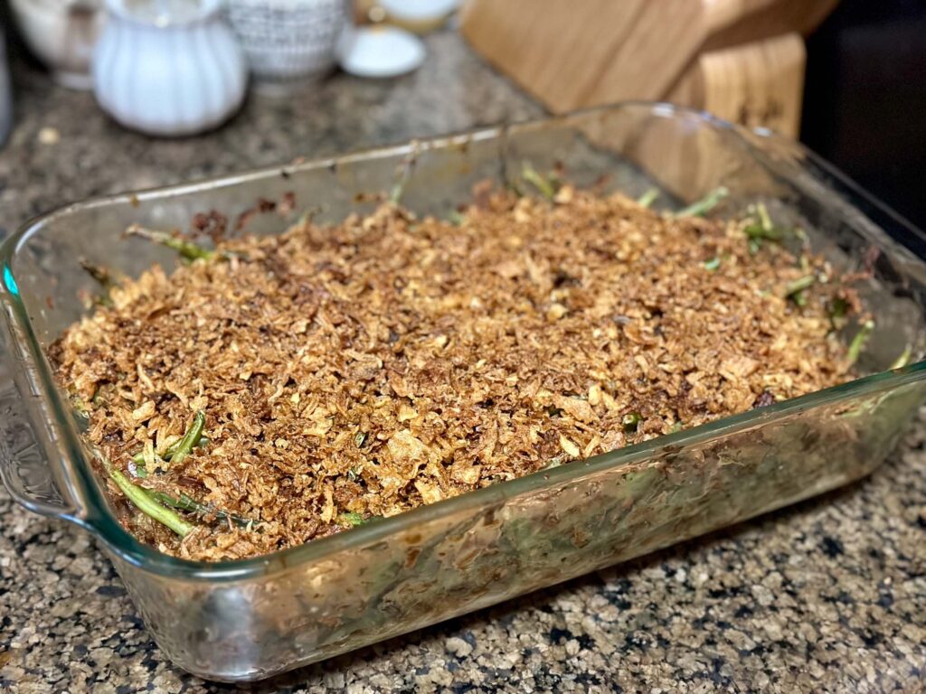 Glass baking dish filled with baked green bean casserole topped with crispy French fried onions.