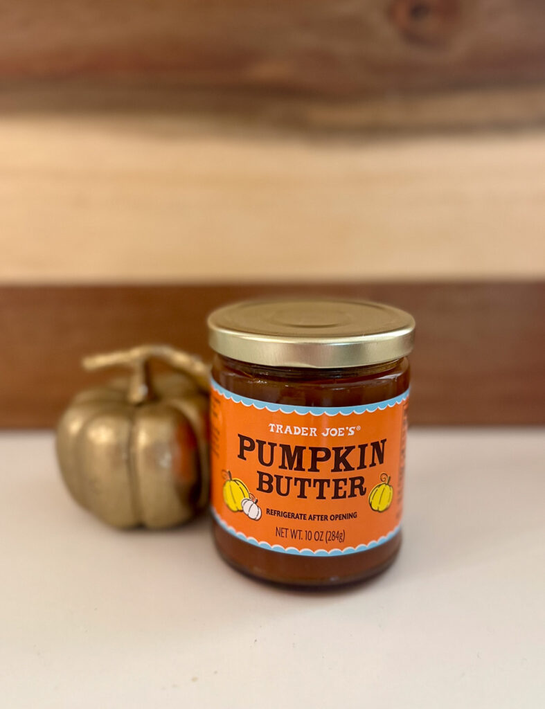 Jar of Trader Joe's Pumpkin Butter sitting on a white countertop with a gold pumpkin in the background