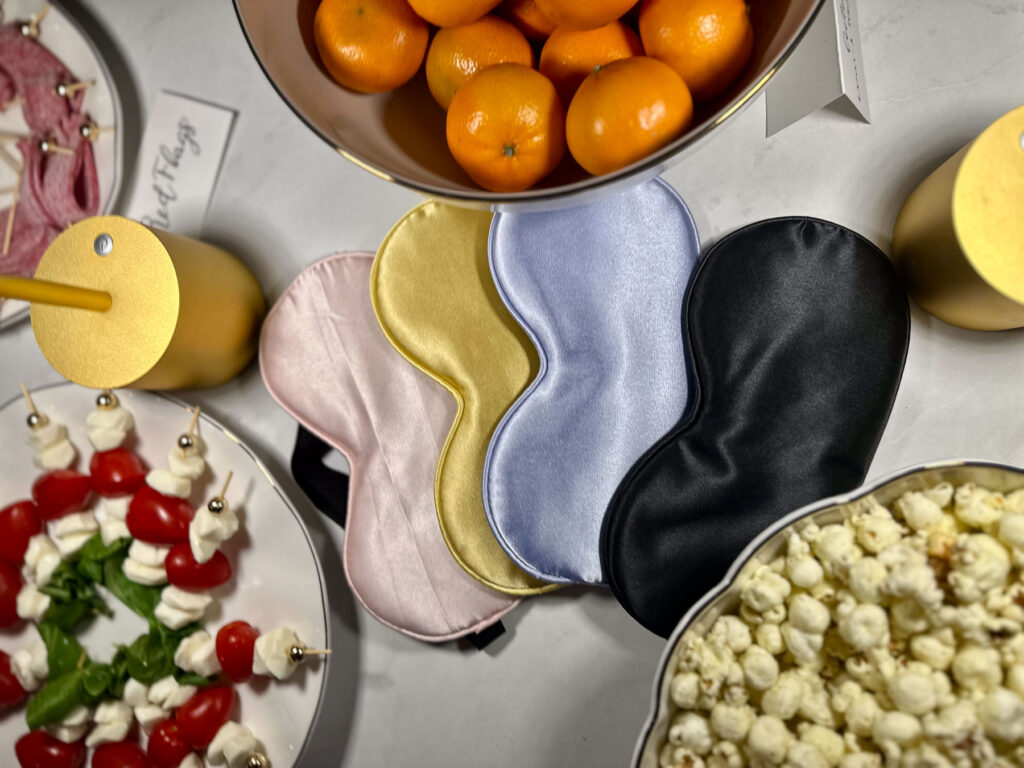 Love Is Blind watch party setup with silk sleep masks, caprese skewers, popcorn, and tangerines in gold bowls.