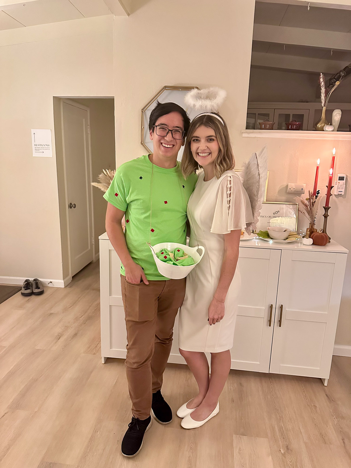 A smiling couple standing in a living room dressed up in a funny 'Holy Guacamole' couple's costume for a Halloween party.