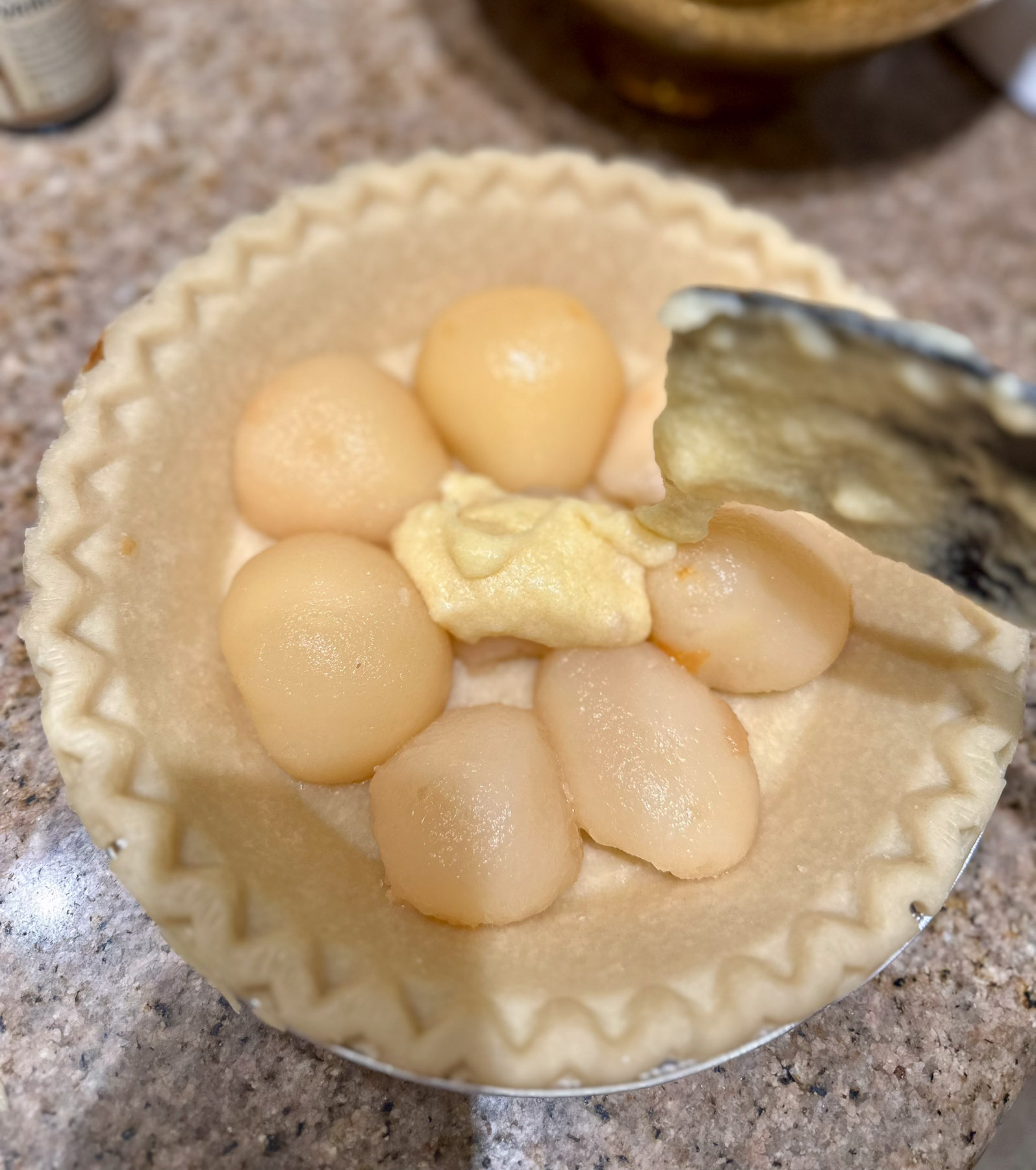 Adding the buttery topping over the pears in the pie shell.