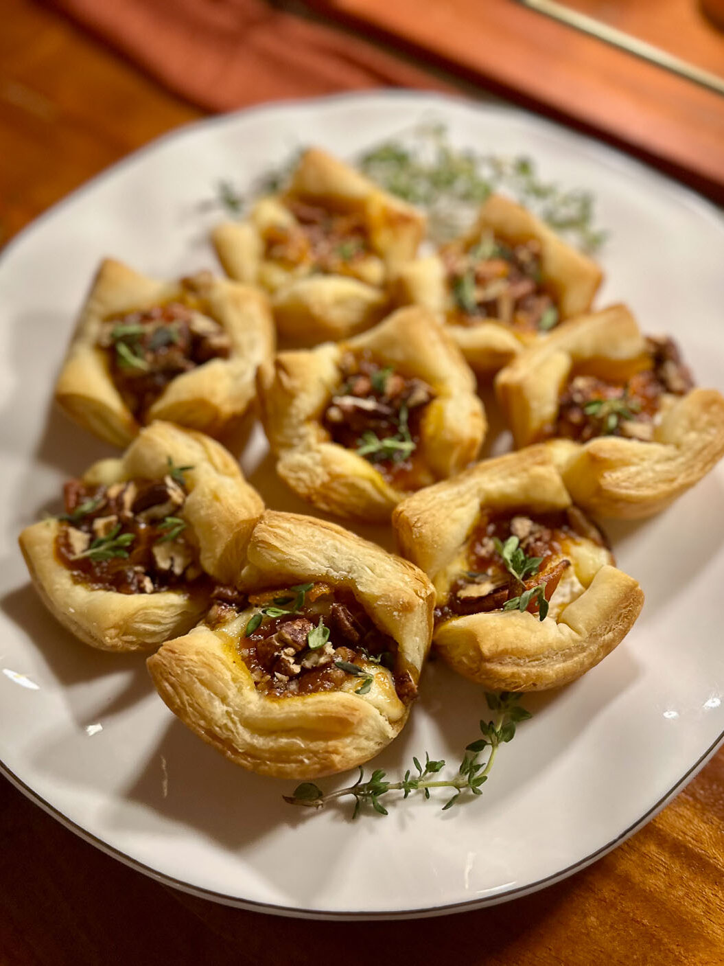 Mini puff pastry brie bites topped with pumpkin butter, pecans, and fresh thyme.