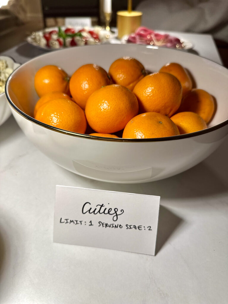 Bowl of tangerines with a handwritten sign reading “Cuties: Limit 1, Serving Size 2,” referencing the Love Is Blind tangerine scene.
