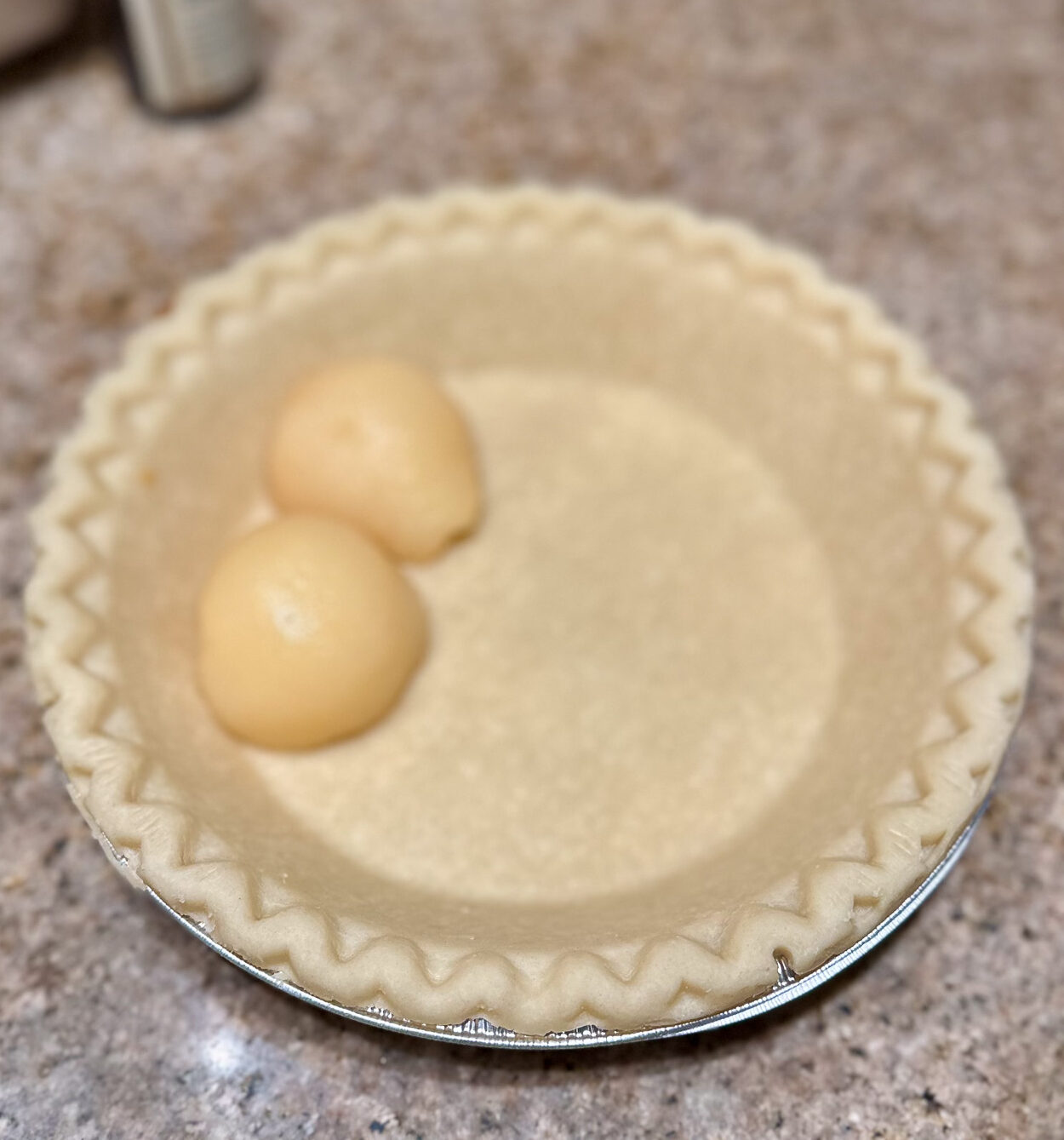 A few canned pear halves placed in an unbaked pie shell to start layering the filling.