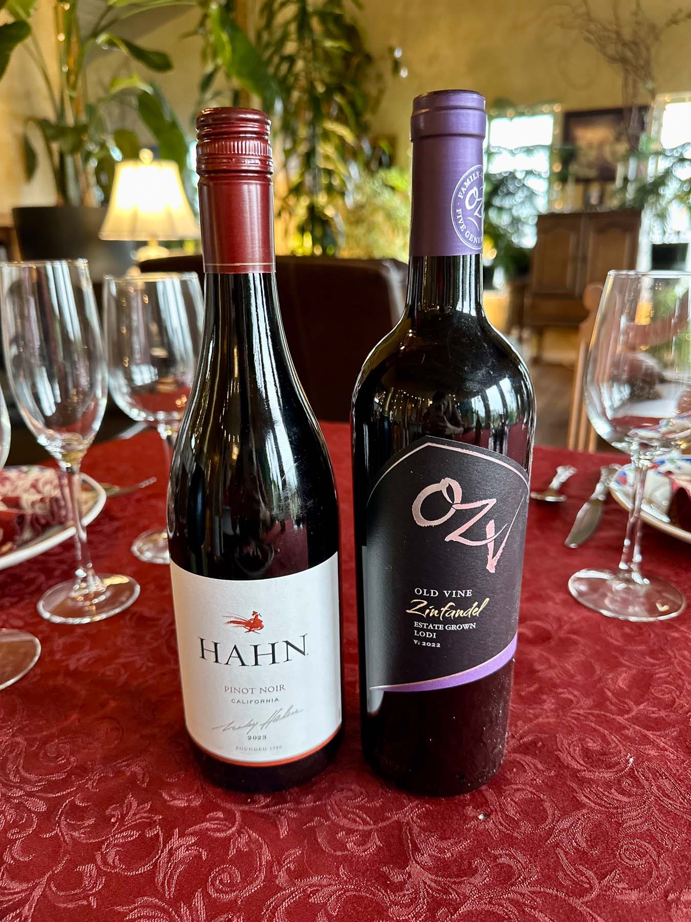 Hahn pinot noir and OZV old vine zinfandel bottles on a red tablecloth surrounded by empty wine glasses during Thanksgiving tasting.