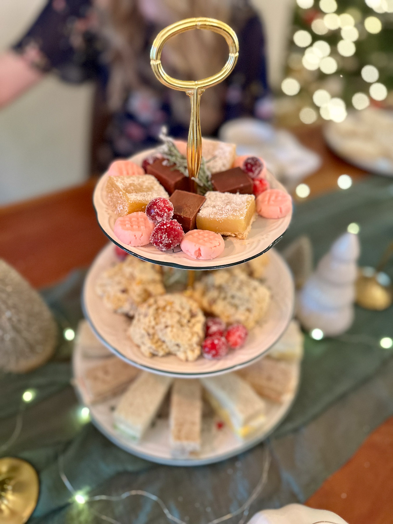 Top tier of a Christmas tea party tray with fudge, butter mints, lemon bars, and sugared cranberries