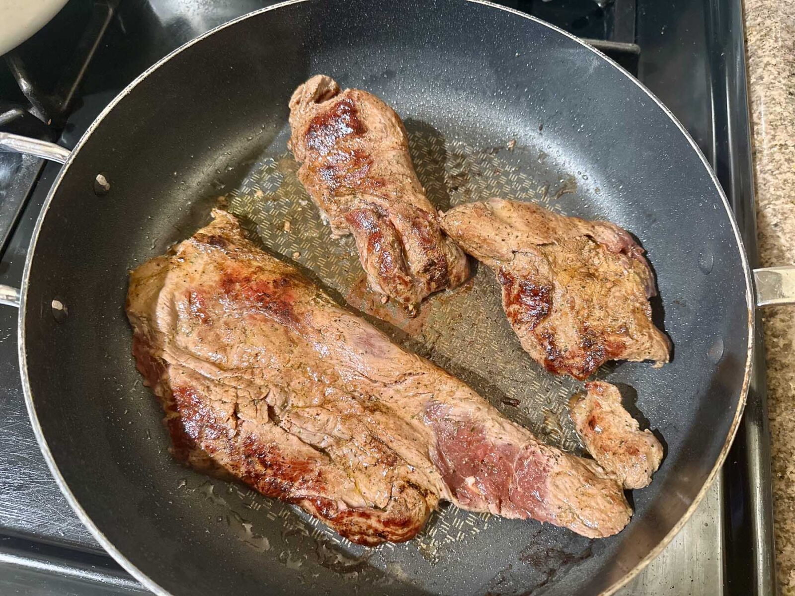 Thinly sliced carne asada pieces searing in a skillet until browned.