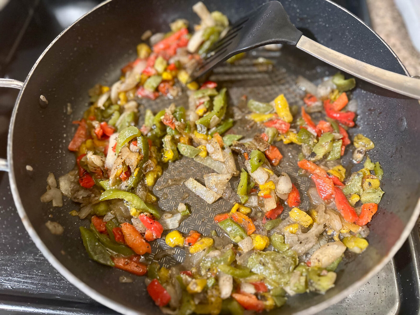 Trader Joe’s fire-roasted peppers and onions sautéing in a skillet.
