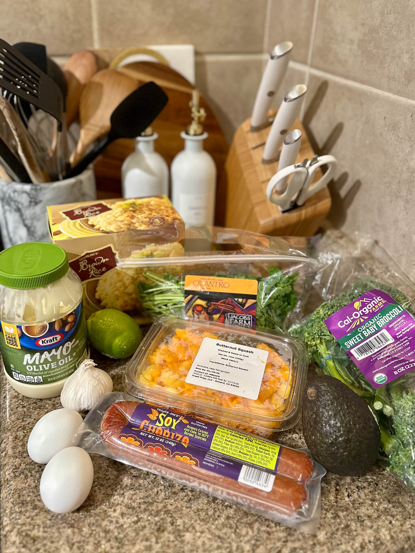 Trader Joe’s ingredients for soy chorizo bowls, including soy chorizo, brown rice, sweet baby broccoli, butternut squash, avocado, eggs, cilantro, garlic, lime, and olive oil mayo.