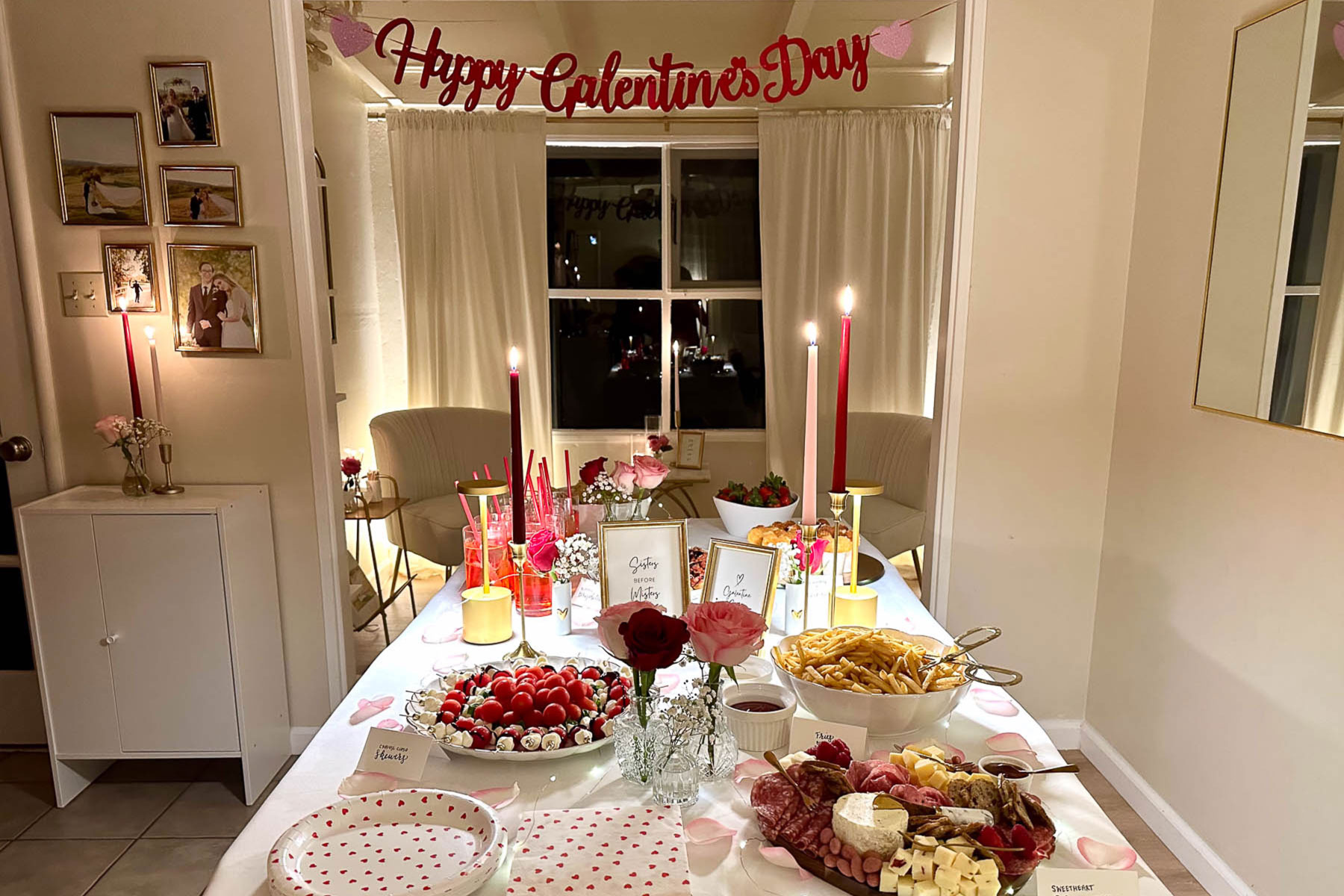 Galentine’s Day party decor and food display featuring charcuterie board, fries, drinks, pink candles, and heart-themed tableware for a girls’ night in.