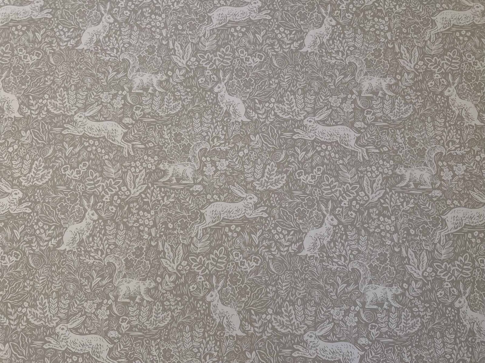 Close-up of neutral peel-and-stick wallpaper with subtle animal and foliage pattern.