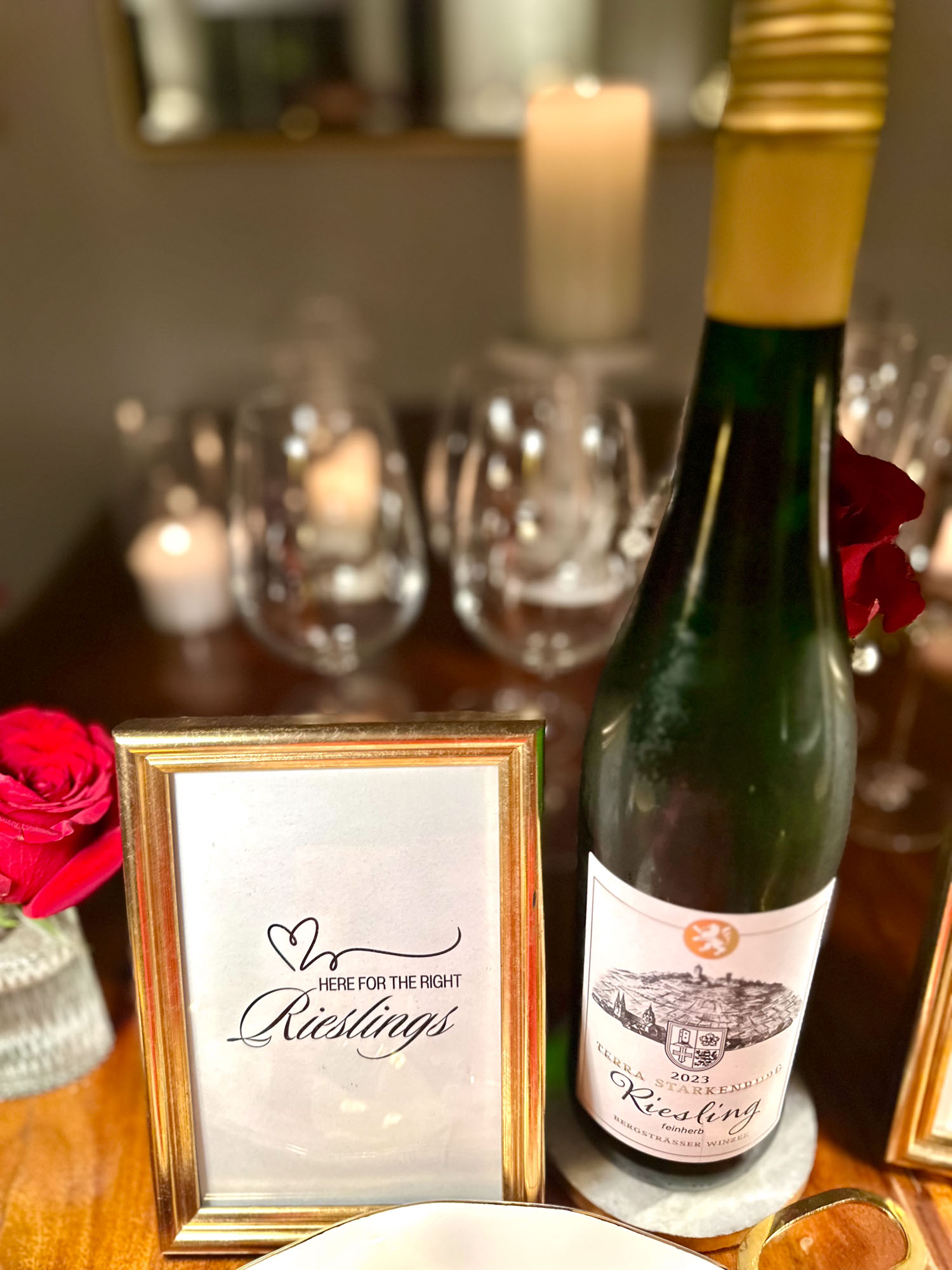 Wine bottle with “Here for the right Rieslings” sign and candlelit glasses in the background