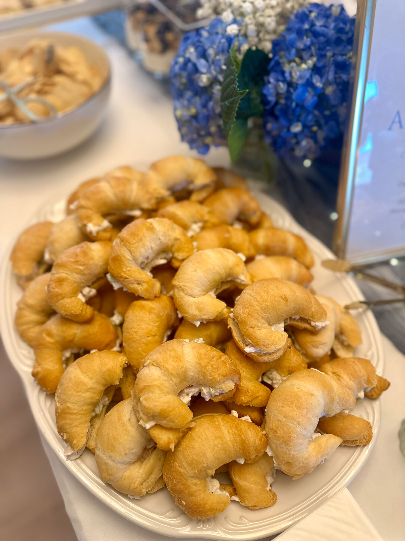 Chicken salad crescent sandwiches styled as “moon” shapes for a baby shower menu.