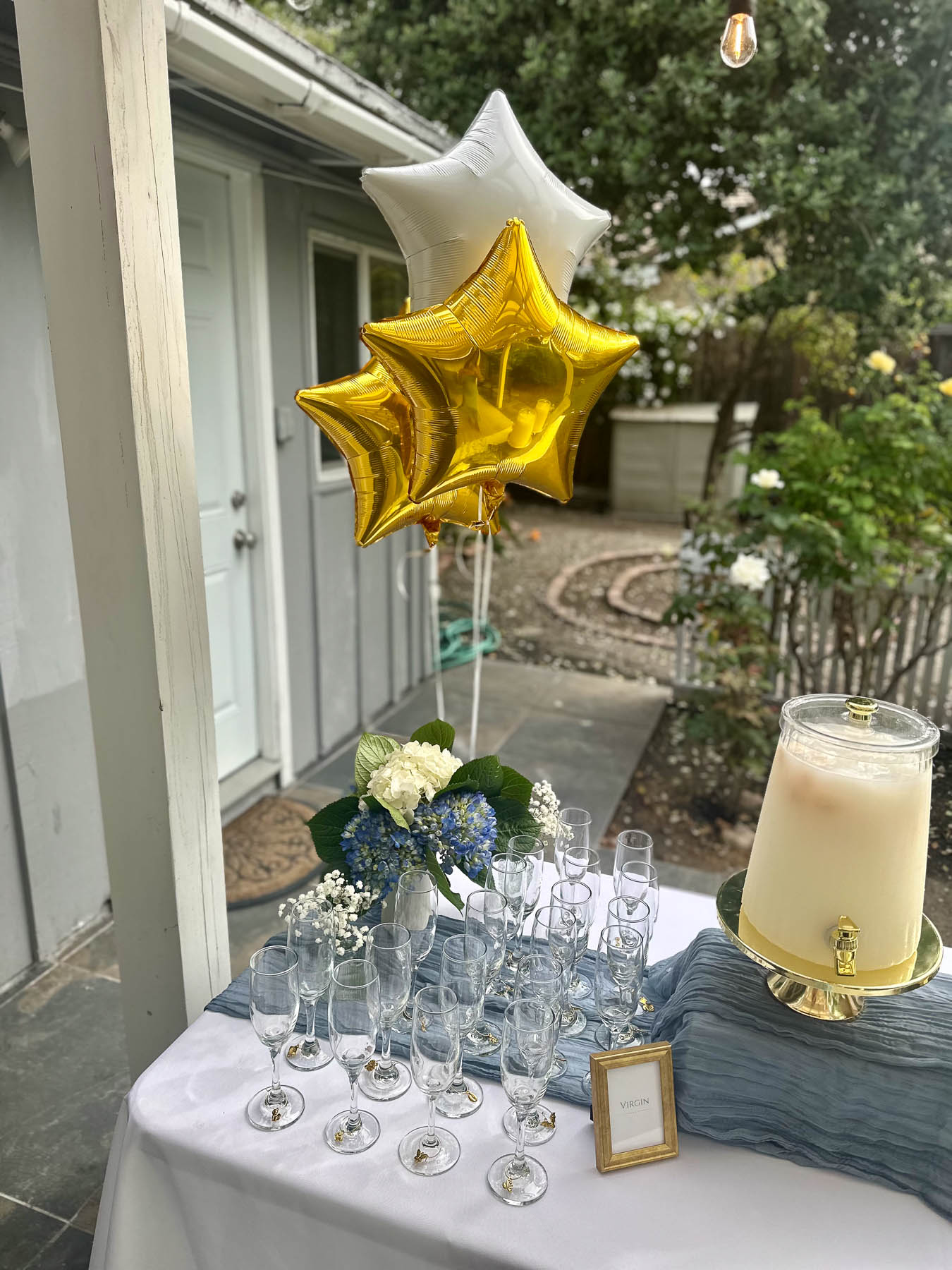Over the Moon baby shower drink station with gold star balloons and lychee mimosa dispenser