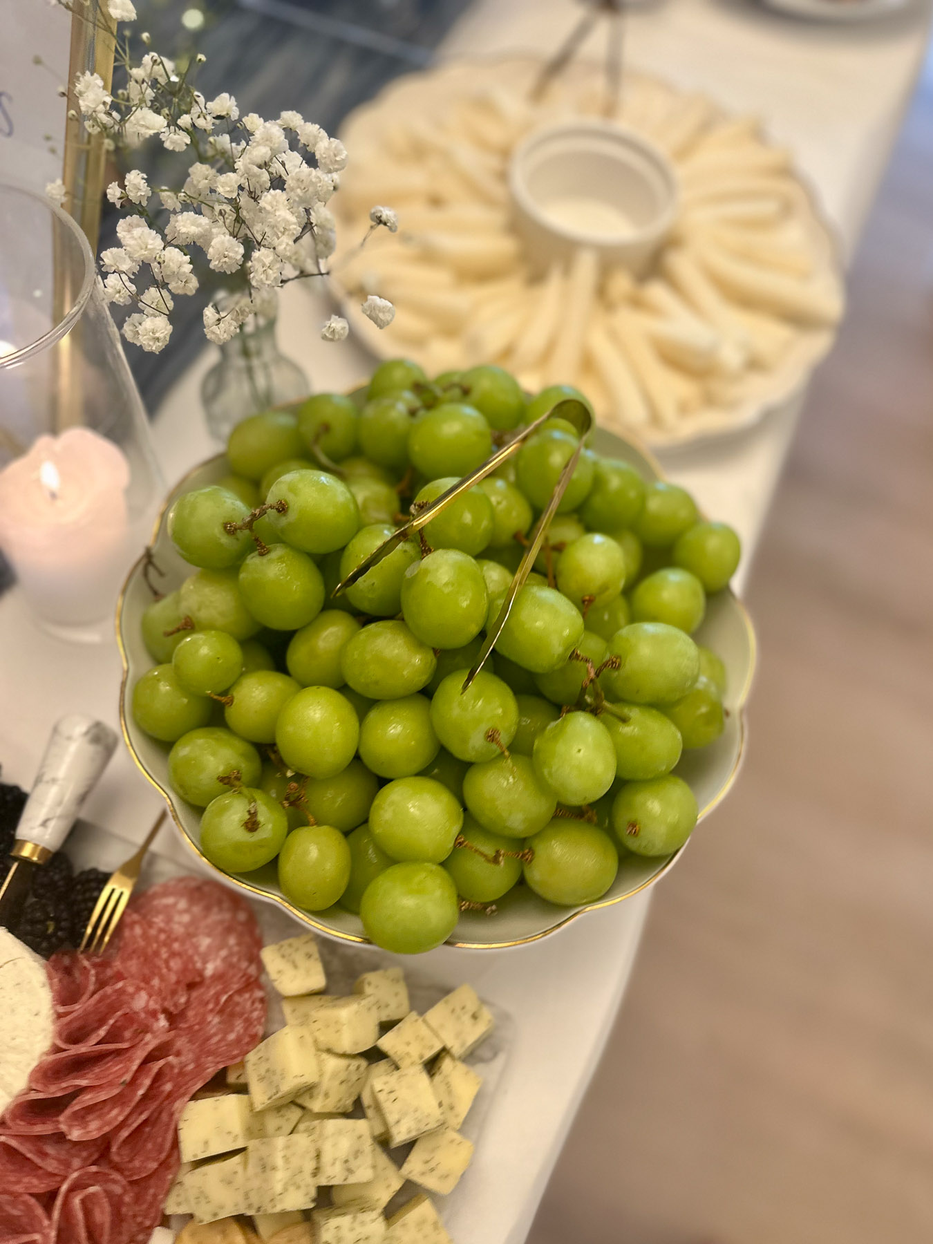 Bowl of green grapes with charcuterie elements on a party table