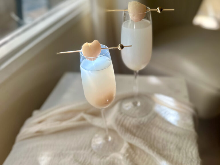 Lychee mimosas in champagne flutes with lychee garnish on cocktail picks.