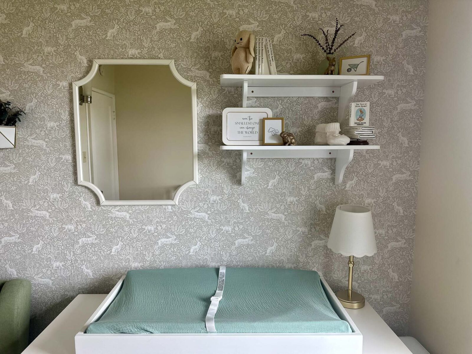Changing table wall styled with mirror and floating shelves.