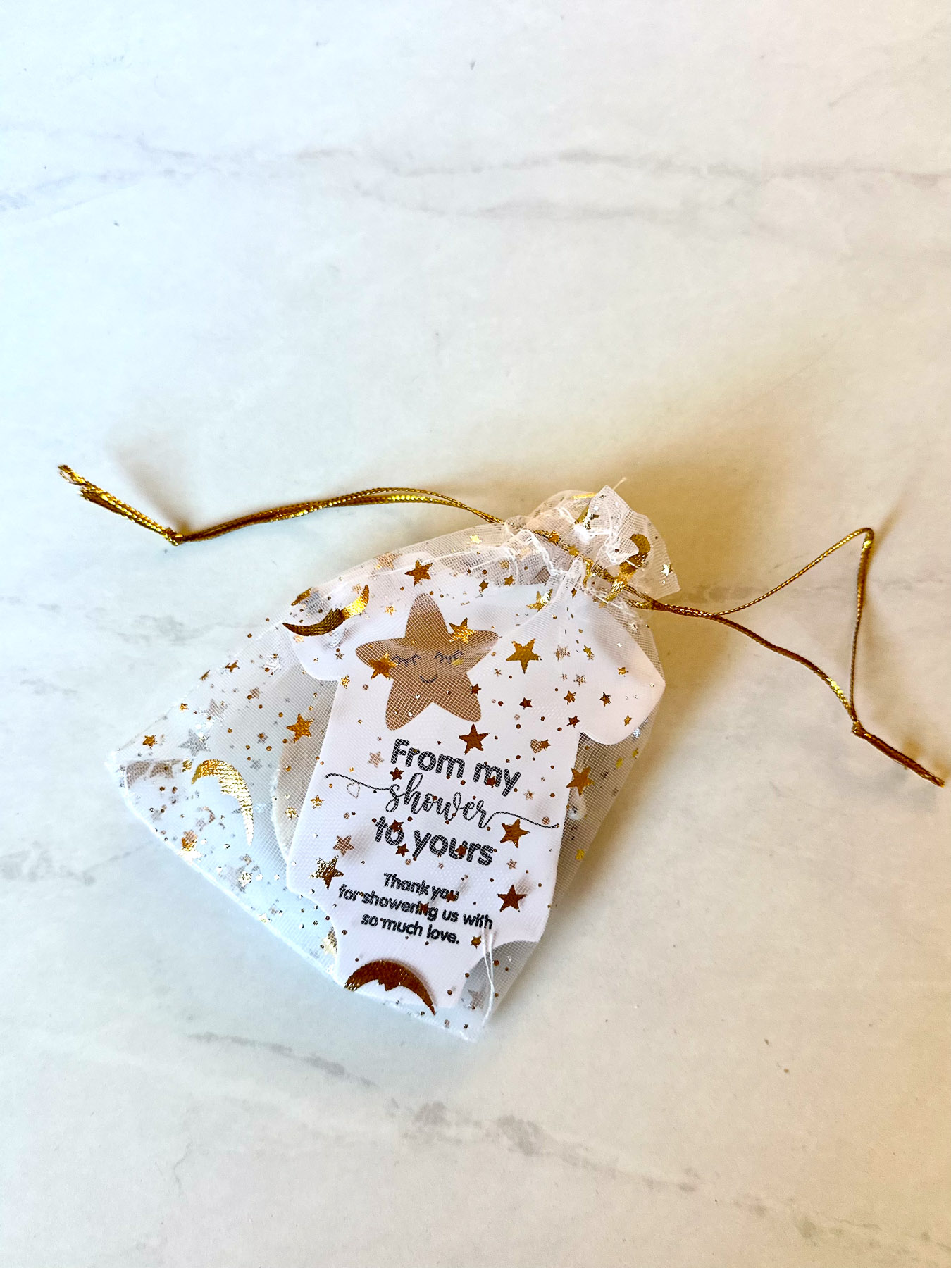 Moon-themed baby shower favor wrapped in sheer star-print bag with tag