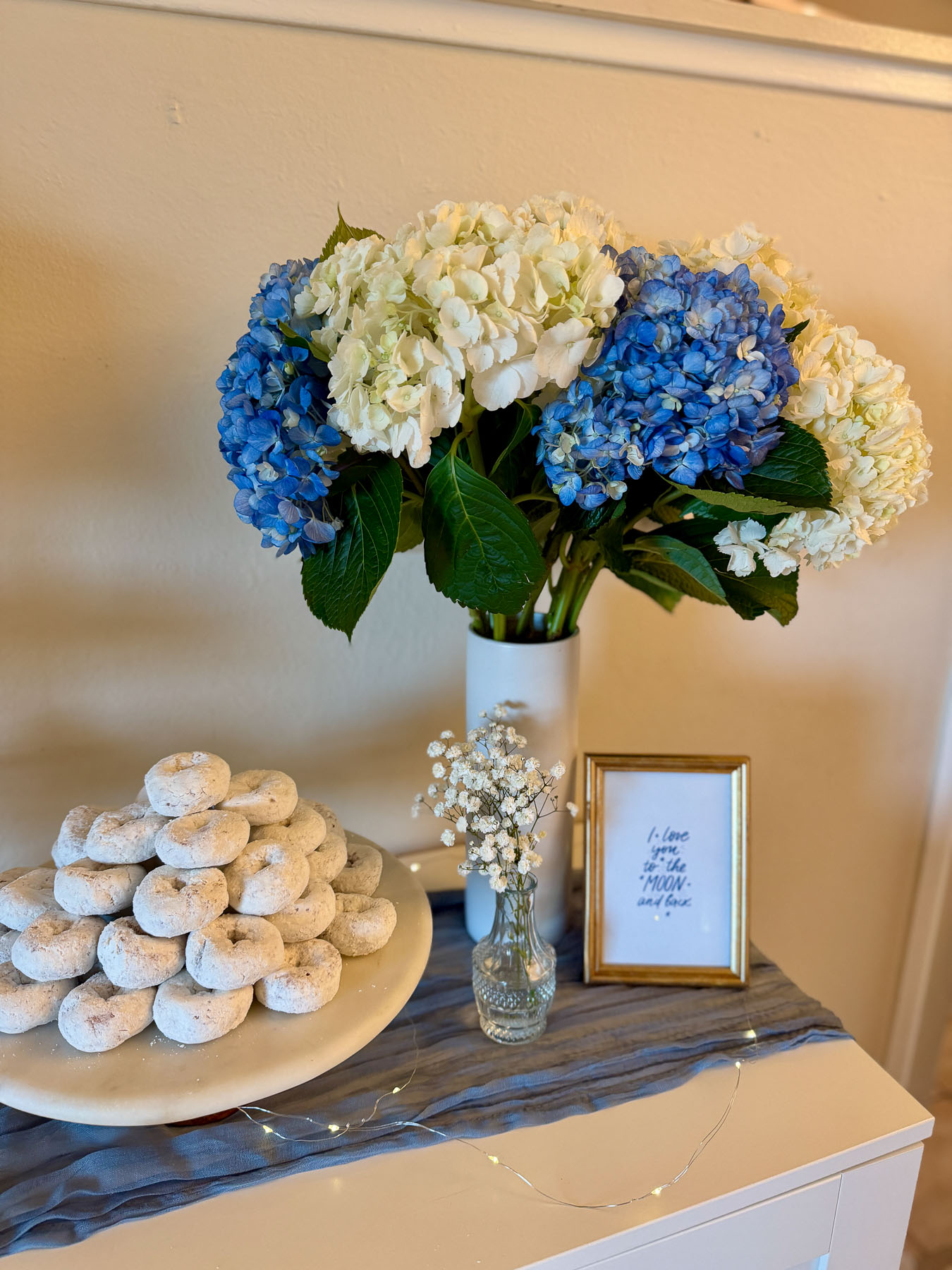 Blue and white hydrangea centerpiece with powdered sugar donuts and baby shower decor