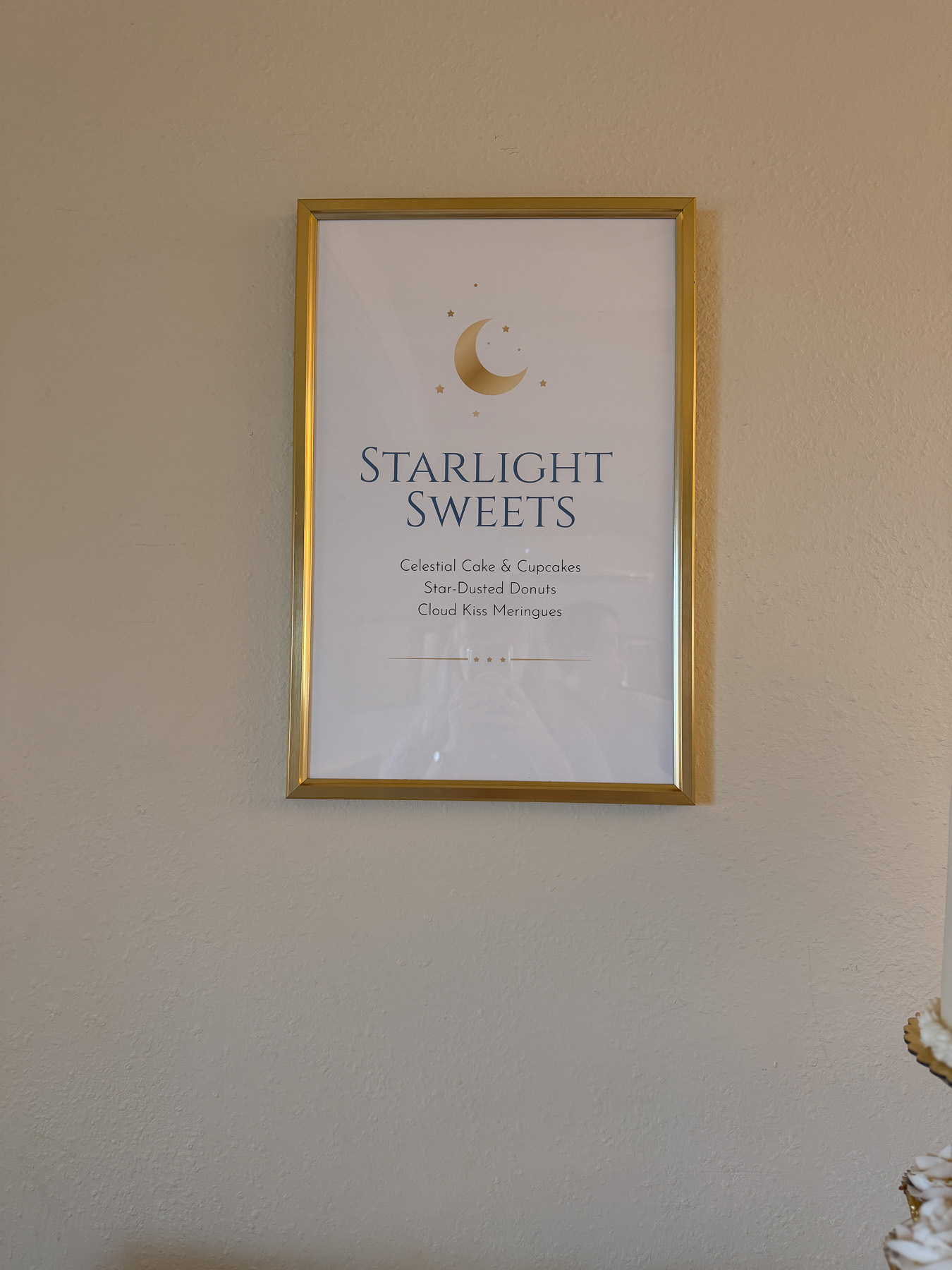 Moon-themed baby shower sign in a gold frame with celestial design that reads "Starlight Sweets: Celestial Cake & Cupcakes, Star-Dusted Donuts, Cloud Kiss Meringues"