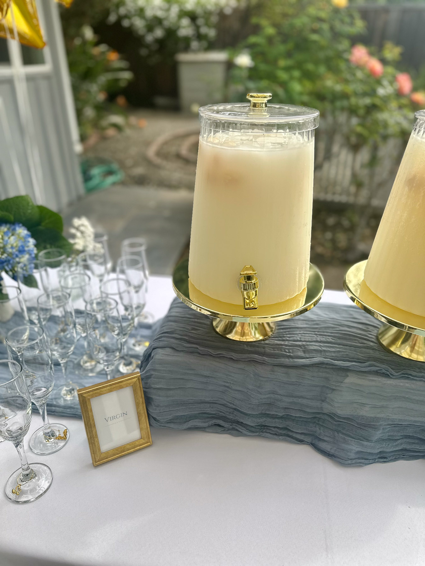 Lychee mimosa dispenser on gold stand with champagne flutes for guests