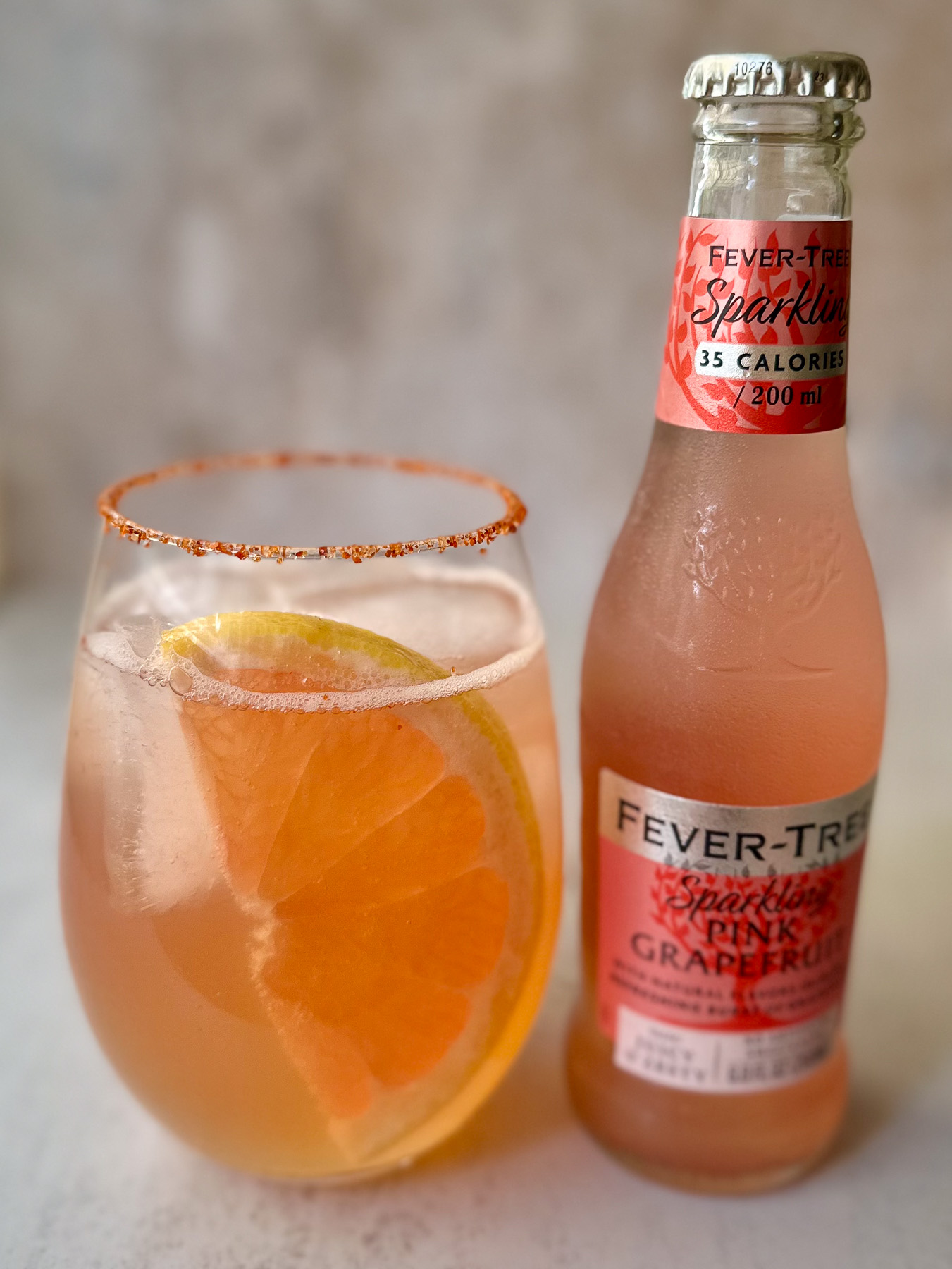 Bubbly grapefruit mocktail with lime and Tajín rim next to Fever-Tree grapefruit soda