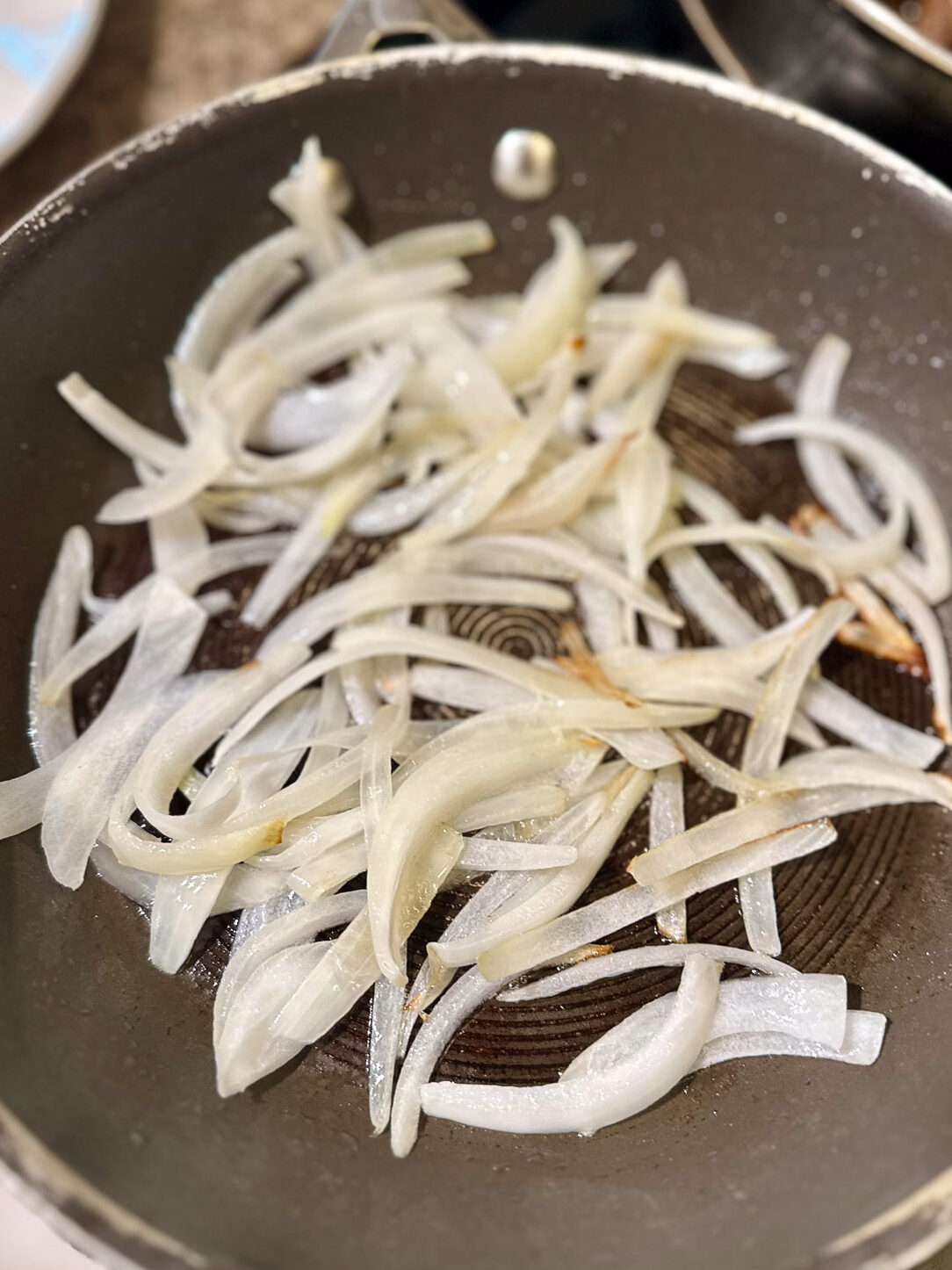 Sautéed sweet onions in a skillet, softened and beginning to brown.