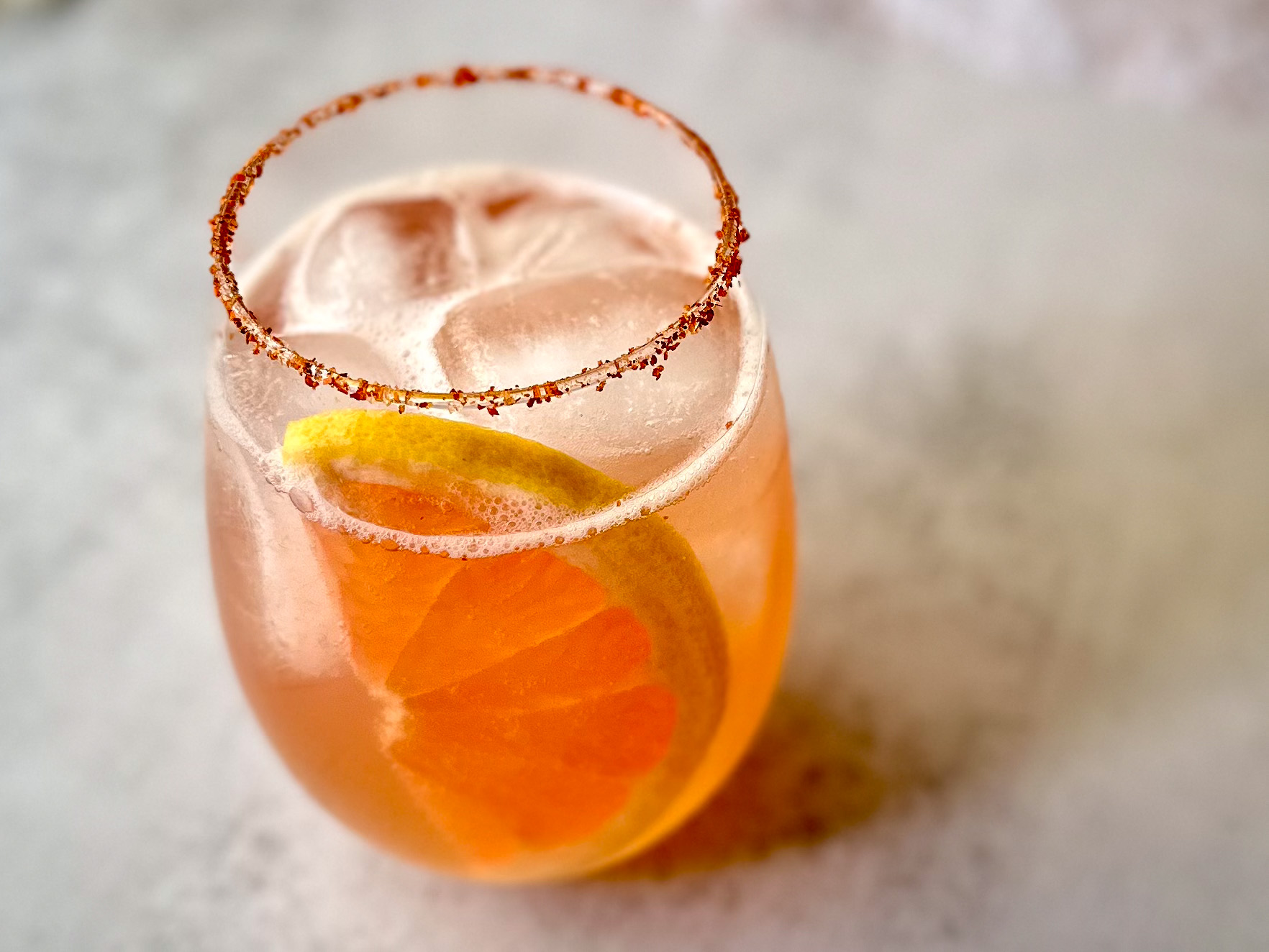 Grapefruit Paloma mocktail with Tajín rim, fresh grapefruit slice, and ice in a lowball glass.