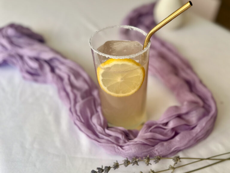 Lavender mocktail with lemon and elderflower in a glass with fresh lavender on a lavender table runner