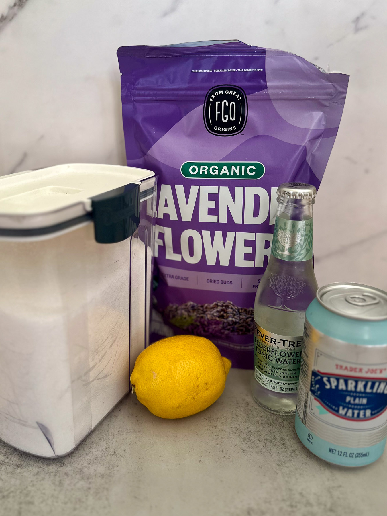 Lavender mocktail ingredients including dried lavender, lemon, elderflower tonic water, and sparkling water